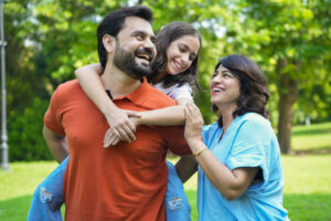 father carrying piggyback his daughter at summer park. family of three enjoying together, Parents bonding love and care. Togetherness. Mom dad with child.