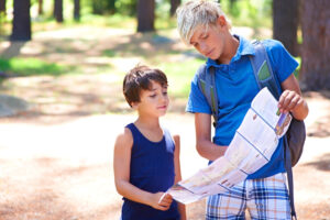 Two boys inspecting a map while hiking in the forest