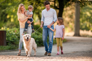 Young family taking their dog for a walk during spring day at the park.