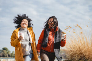 Two female friends are outdoors walking in the city and laughing