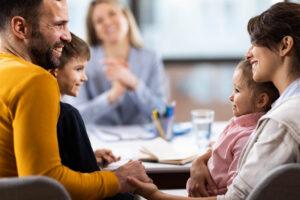 Happy parents and their children having a meeting at family therapist in the office.