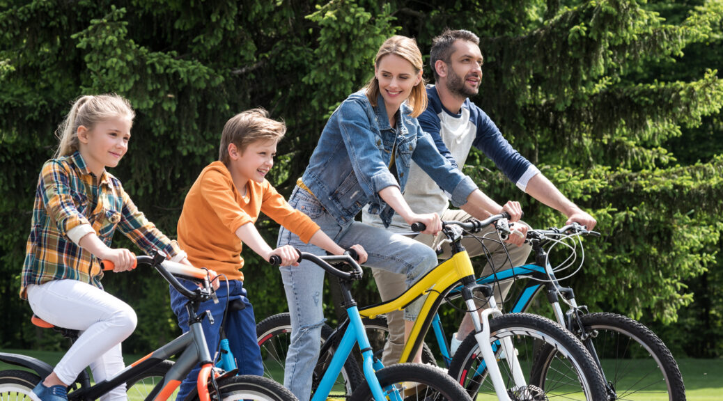 happy family riding bicycles while spending time together in summer park
