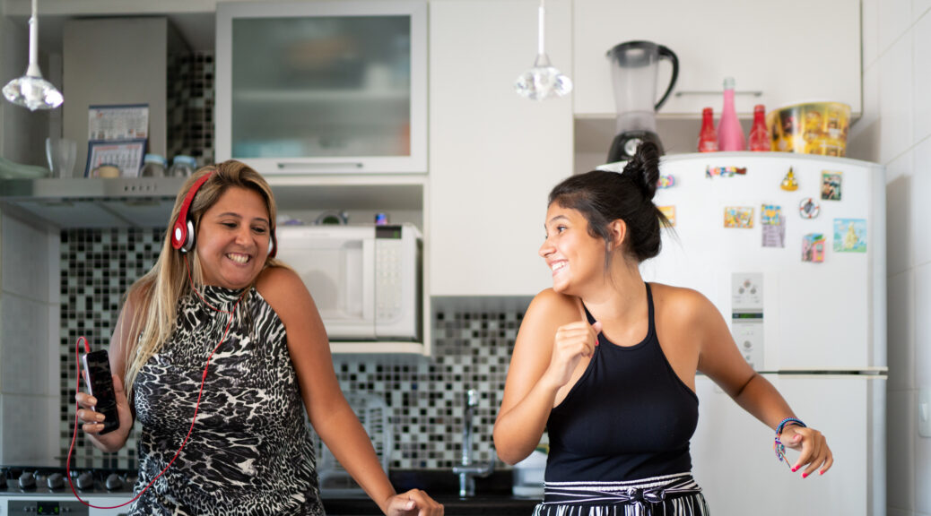 Mother and daughter having fun together while dancing in the kitchen